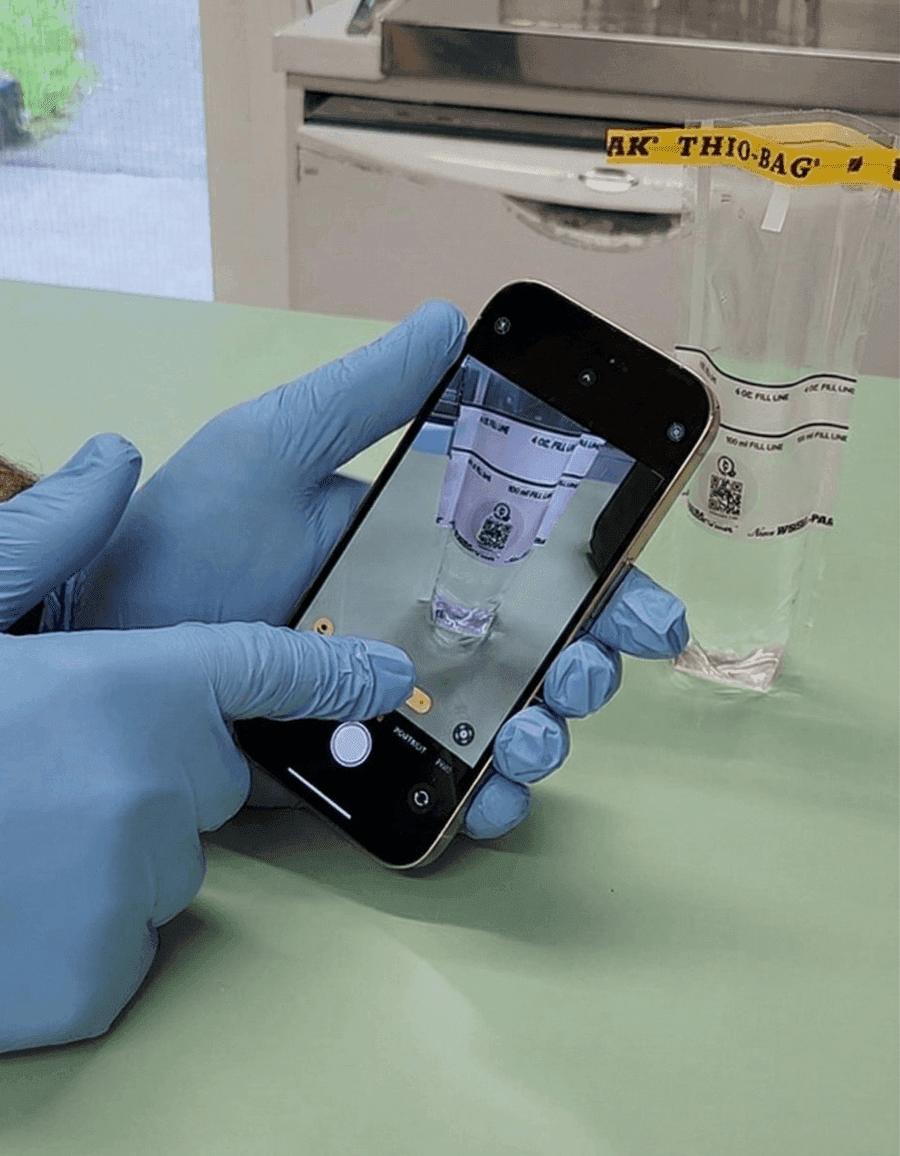 Operator filling a sterile sample bag and scanning the QR code.